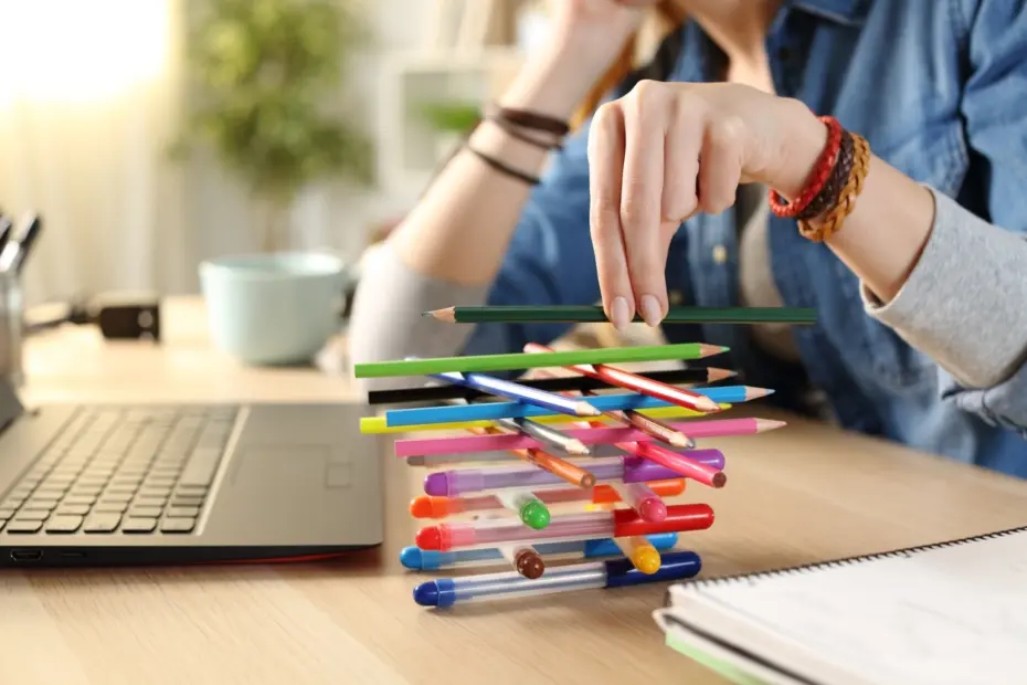 Étudiant jouant avec des stylos sur un bureau